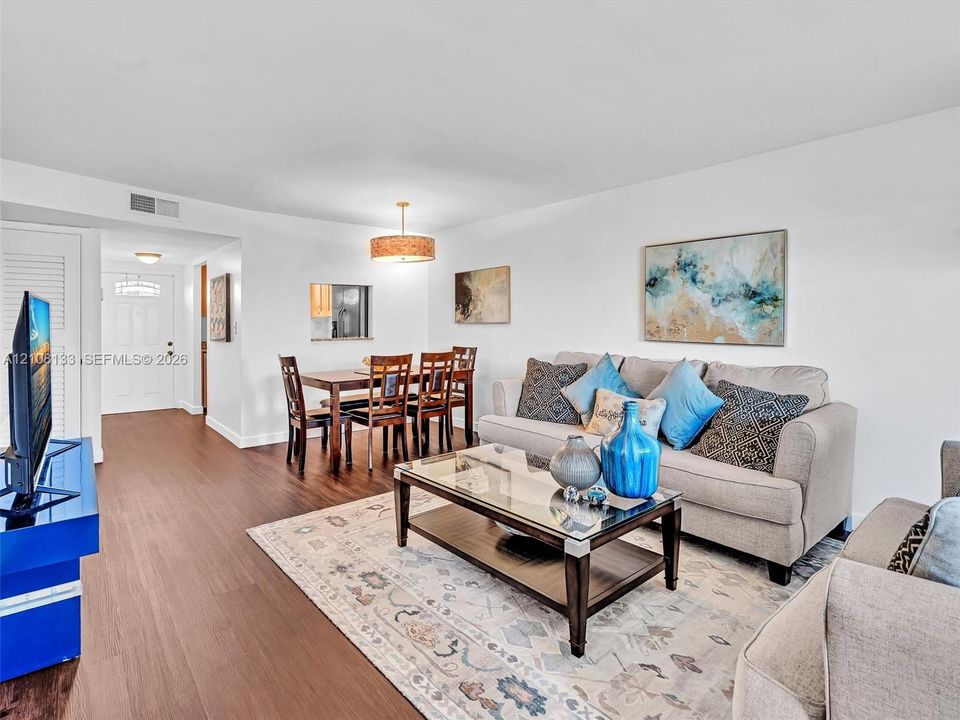 Living area featuring wood-finish flooring, a drum-style pendant light fixture, and a wall cutout