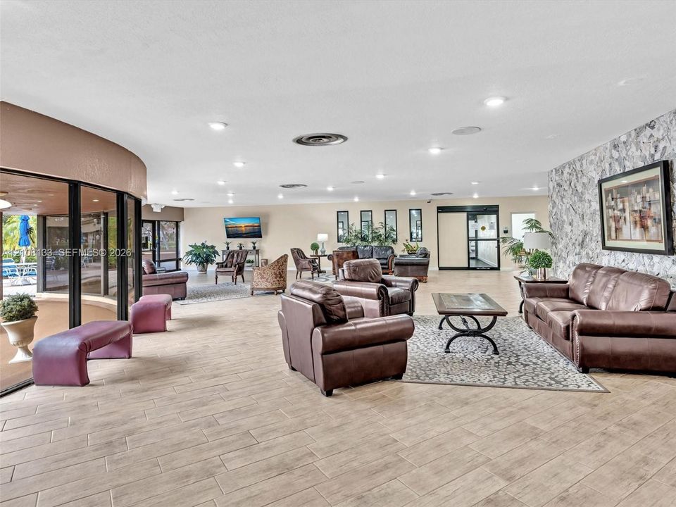 Open floor plan featuring wood-finish flooring, recessed lighting, and a floor-to-ceiling stone-textured accent wall