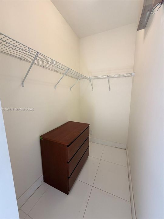 Storage area featuring white tile flooring and wall-mounted wire shelving