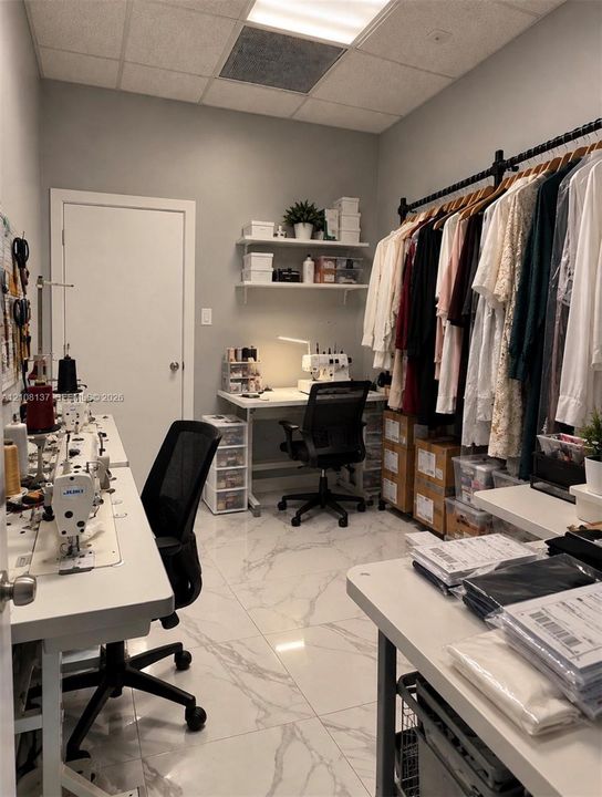 Interior room featuring polished stone-finish floor tile, installed wall shelving, and a wall-mounted clothing rod