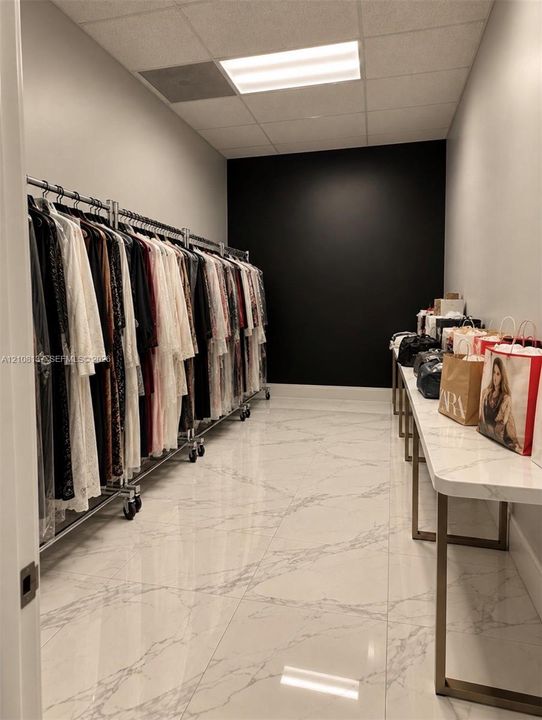 Spacious storage area featuring polished stone-look tile flooring, a charcoal-toned accent wall, and inset ceiling lighting