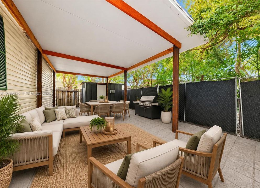 Covered patio featuring a solid roof structure, wood-finish support beams, light-toned concrete pavers, and perimeter privacy fencing