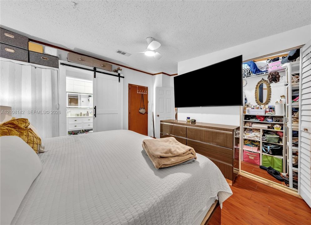 Wood-finish flooring, white sliding barn door with black hardware, and built-in closet shelving