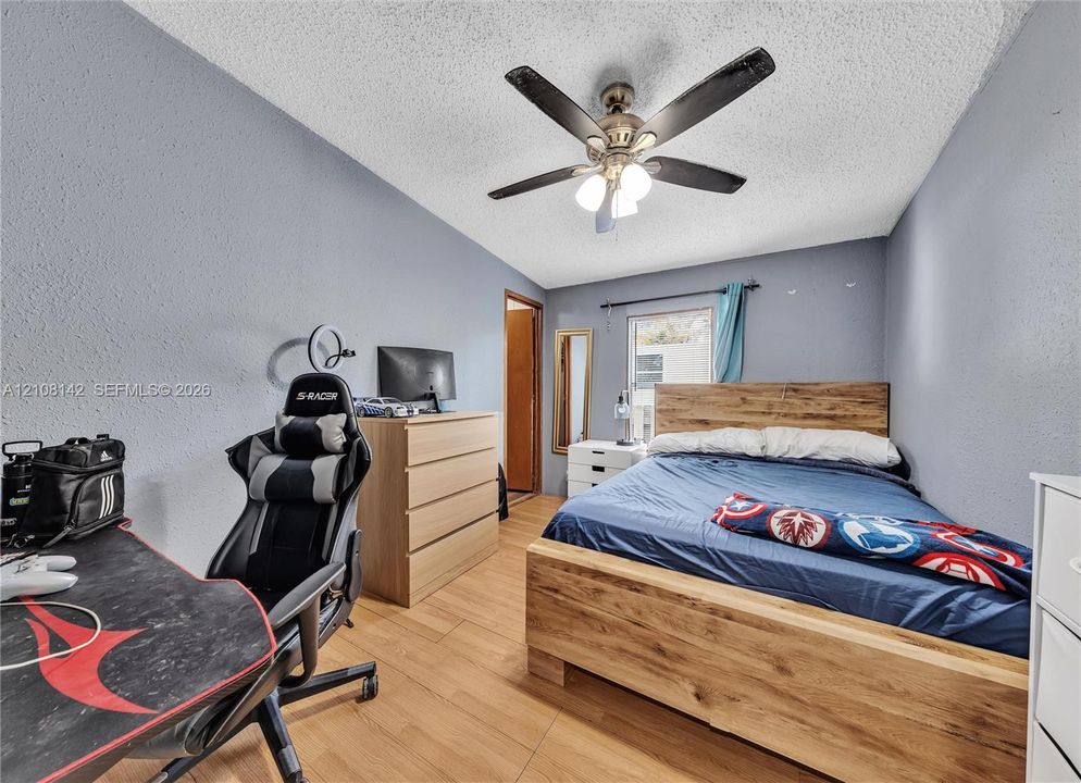 Wood-finish flooring, textured ceiling, and a ceiling fan with integrated lighting