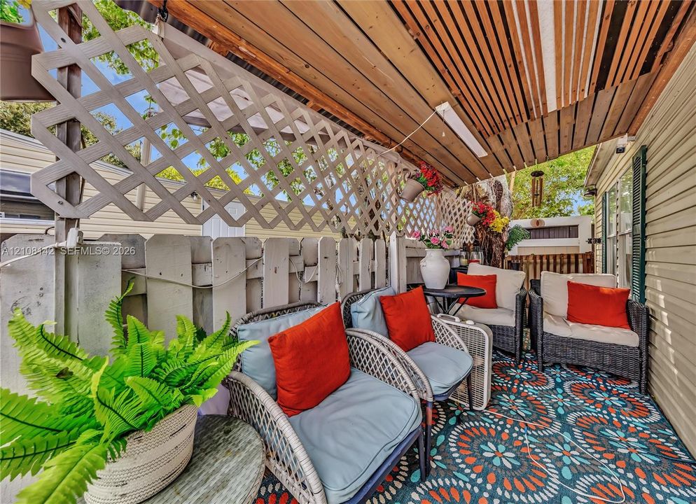 Covered outdoor patio featuring a wood-slat ceiling and decorative diamond-patterned lattice privacy screening