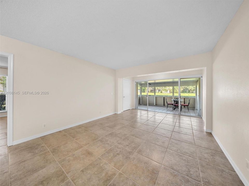 Neutral-toned interior featuring large-format ceramic tile flooring, sliding glass doors, and a screened-in lanai