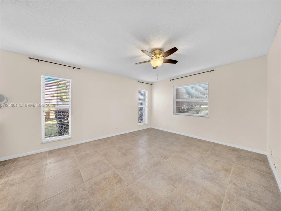 Neutral-toned tile flooring, multi-pane windows with horizontal blinds, and a central ceiling fan with integrated lighting