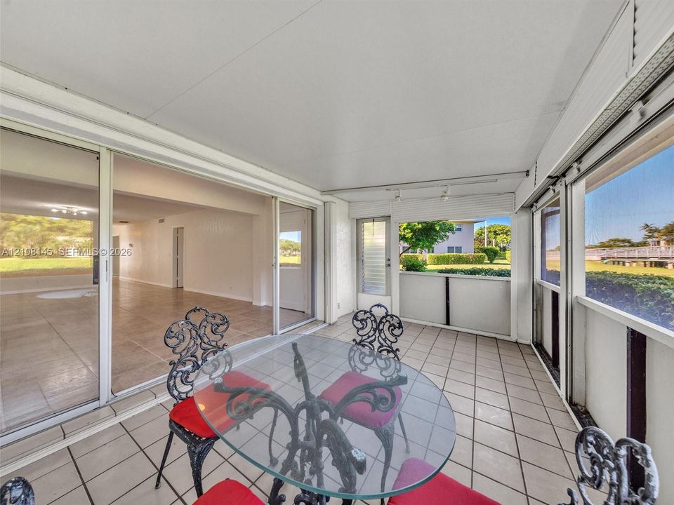 Enclosed patio featuring floor-to-ceiling screen panels, sliding glass door entry, and tiled flooring