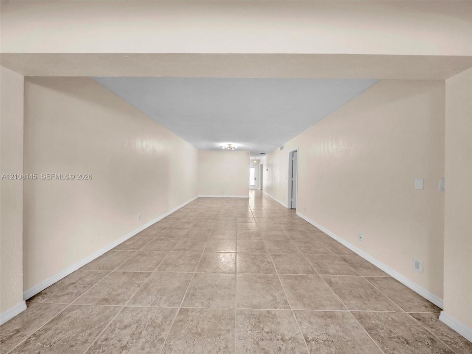 Expansive room featuring neutral wall paint, large format tile flooring, and a recessed ceiling design