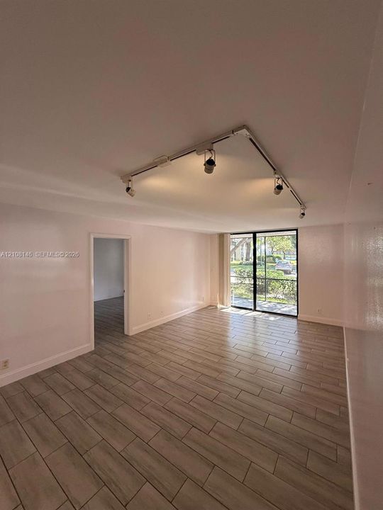 Interior space featuring wood-finish tile flooring, ceiling-mounted track lighting, and sliding glass doors with screen enclosure