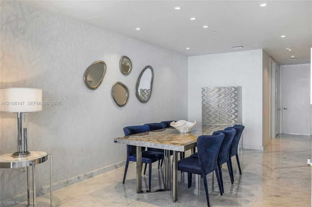 Interior space featuring polished stone flooring, textured wall covering, and recessed lighting throughout