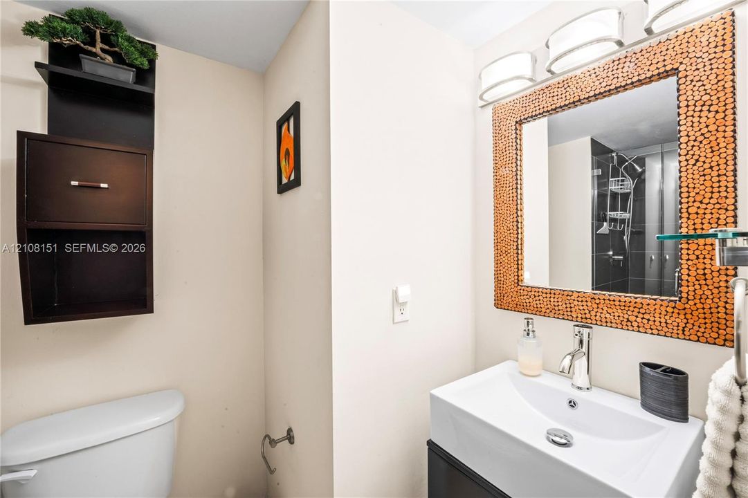 Wall-mounted cabinetry, integrated mirror with textured surround, triple-light vanity fixture, rectangular ceramic sink, and single-lever chrome faucet