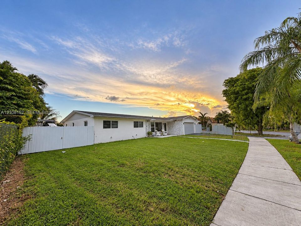 Single-story exterior featuring white stucco siding, a stone facade accent, an attached garage, and a privacy fence