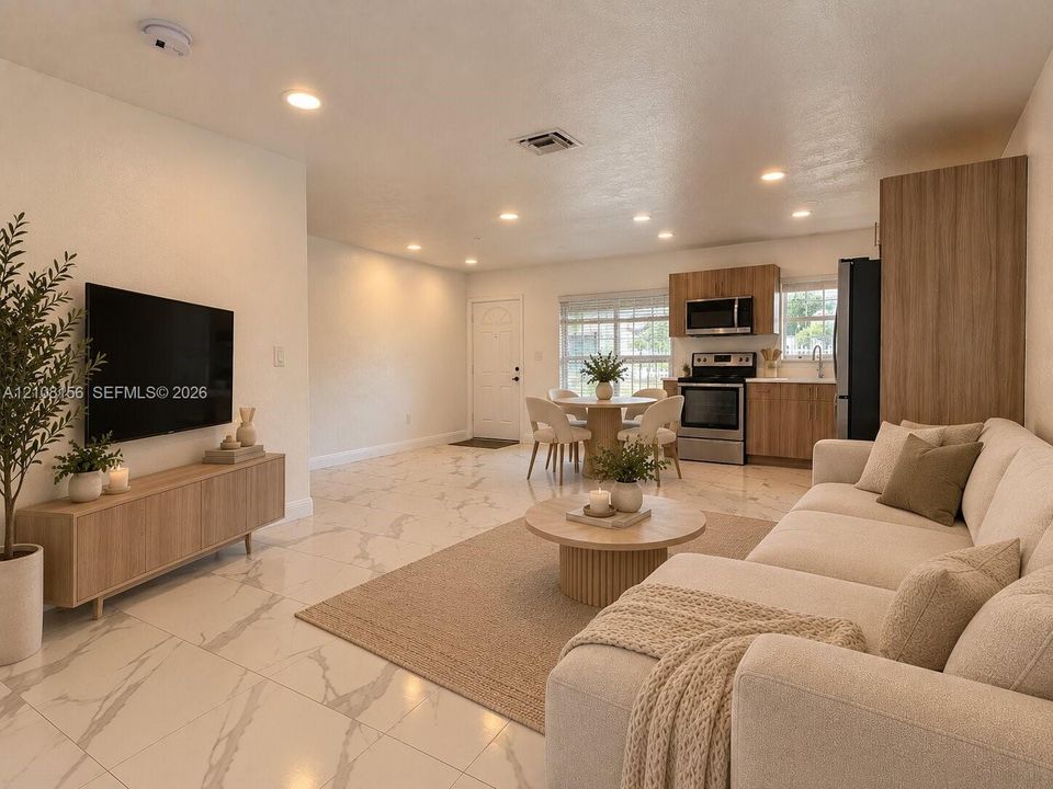 Large-format tile flooring with marble-style veining, recessed lighting, and kitchen featuring wood-finish cabinetry, stainless steel appliances, and built-in pantry storage