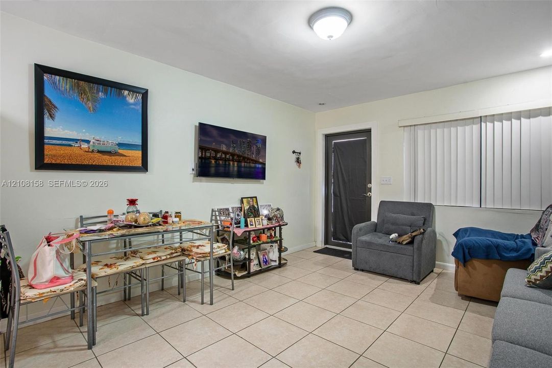 Neutral-toned ceramic tile flooring, ceiling-mounted light fixture, and vertical window blinds