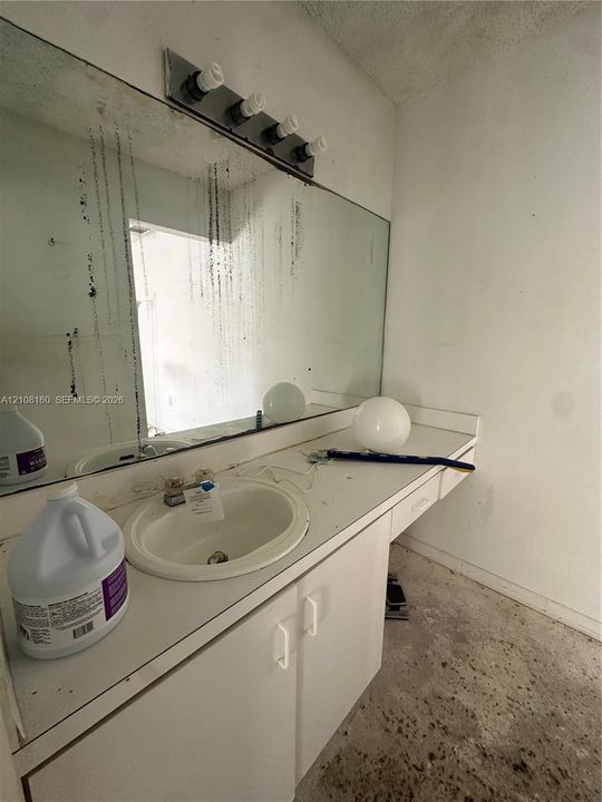 Vanity featuring an integrated sink, built-in cabinetry, and a full-width wall-mounted mirror with an attached four-light fixture