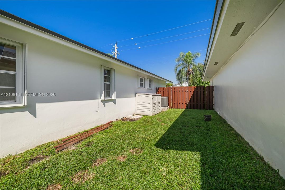 Side yard featuring white stucco exterior walls, a grass lawn, and a solid wood privacy fence