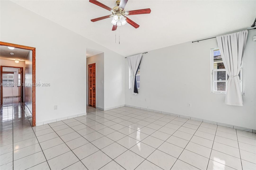 Interior space featuring light-colored tile flooring, vaulted ceilings, and a central ceiling fan with multi-light fixture