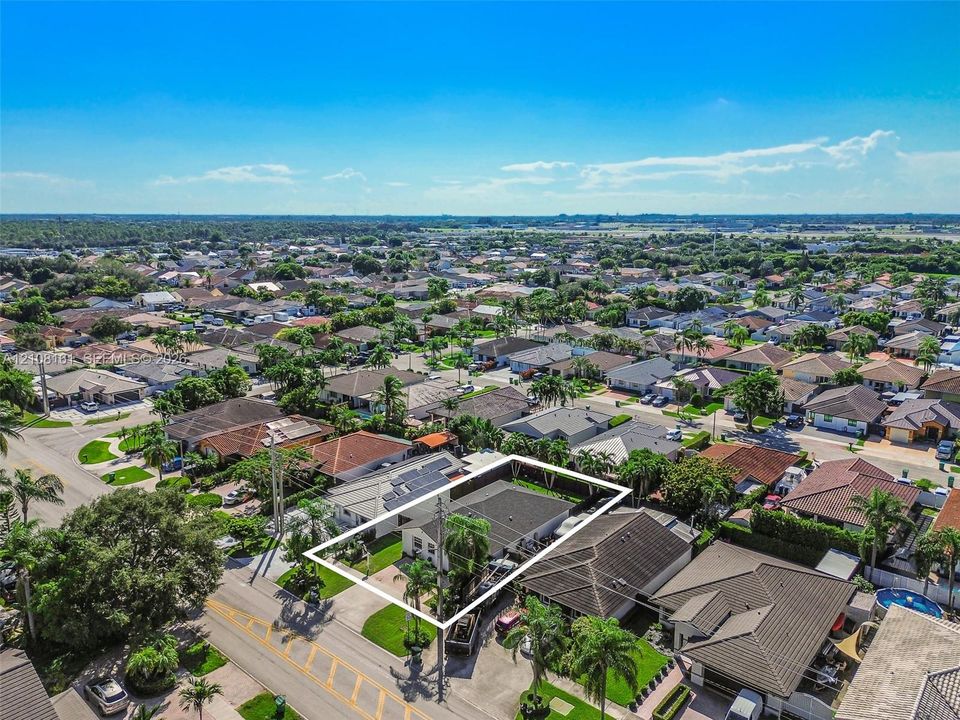Aerial perspective of property featuring a fenced perimeter, solar panels, and manicured landscaping
