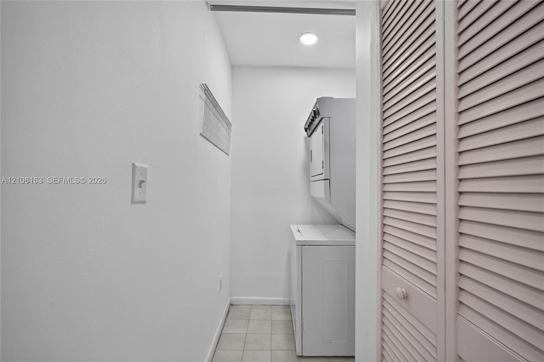 Utility space featuring tile flooring, recessed lighting, and louvered closet doors