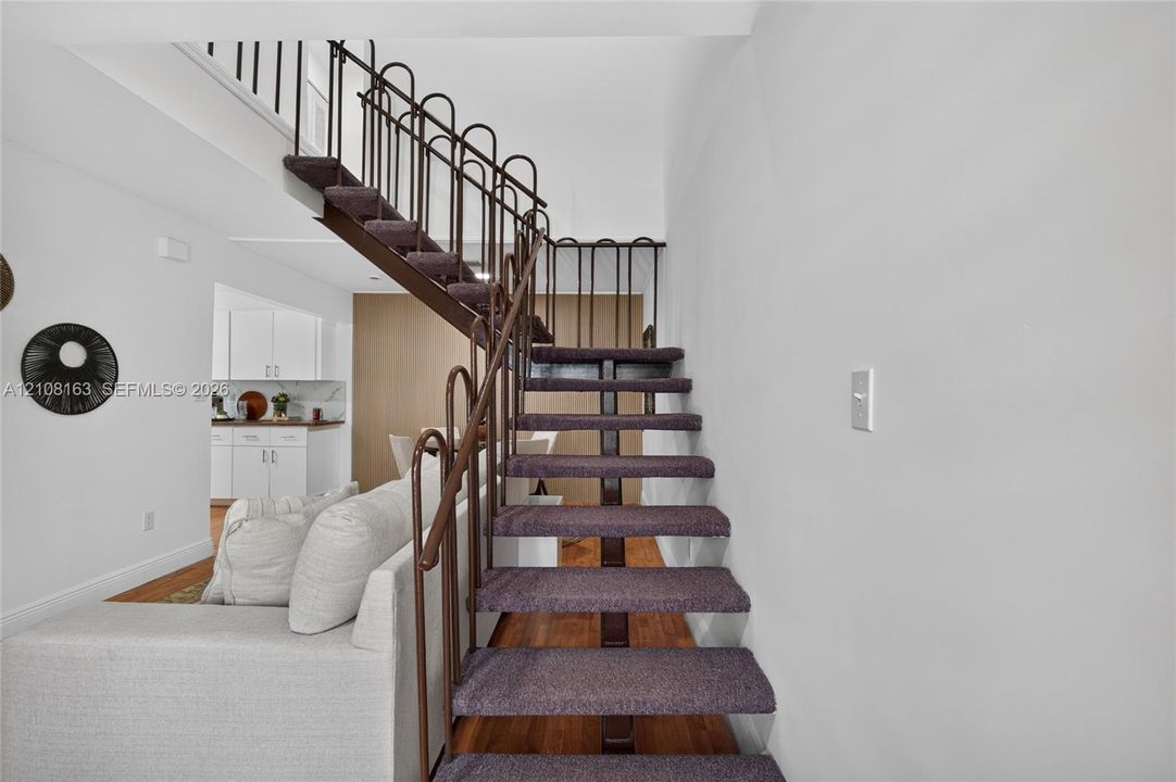 Open-riser staircase featuring metal railings and carpeted treads