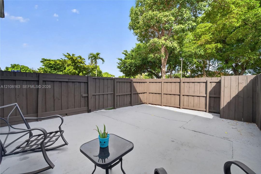 Fenced-in private patio featuring a concrete surface and dark-stained wood privacy wall