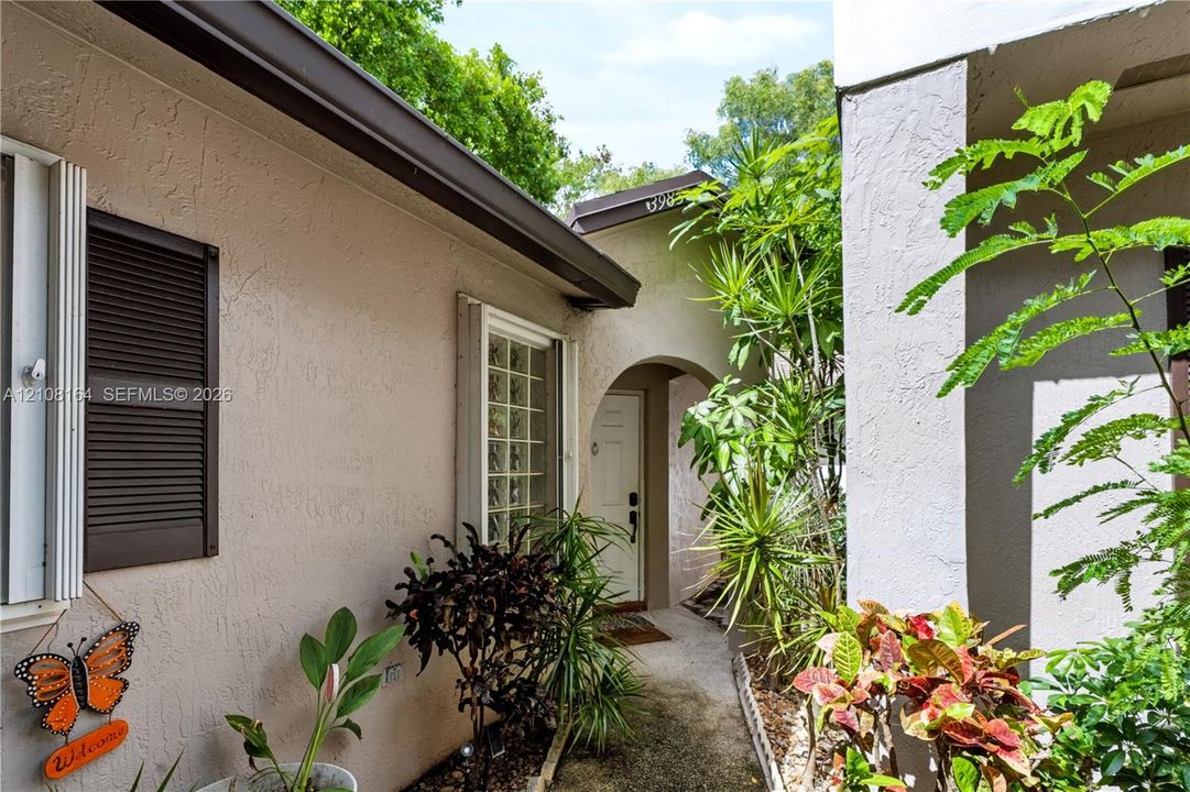 Stucco exterior featuring arched entry, decorative window shutters, and a recessed front door