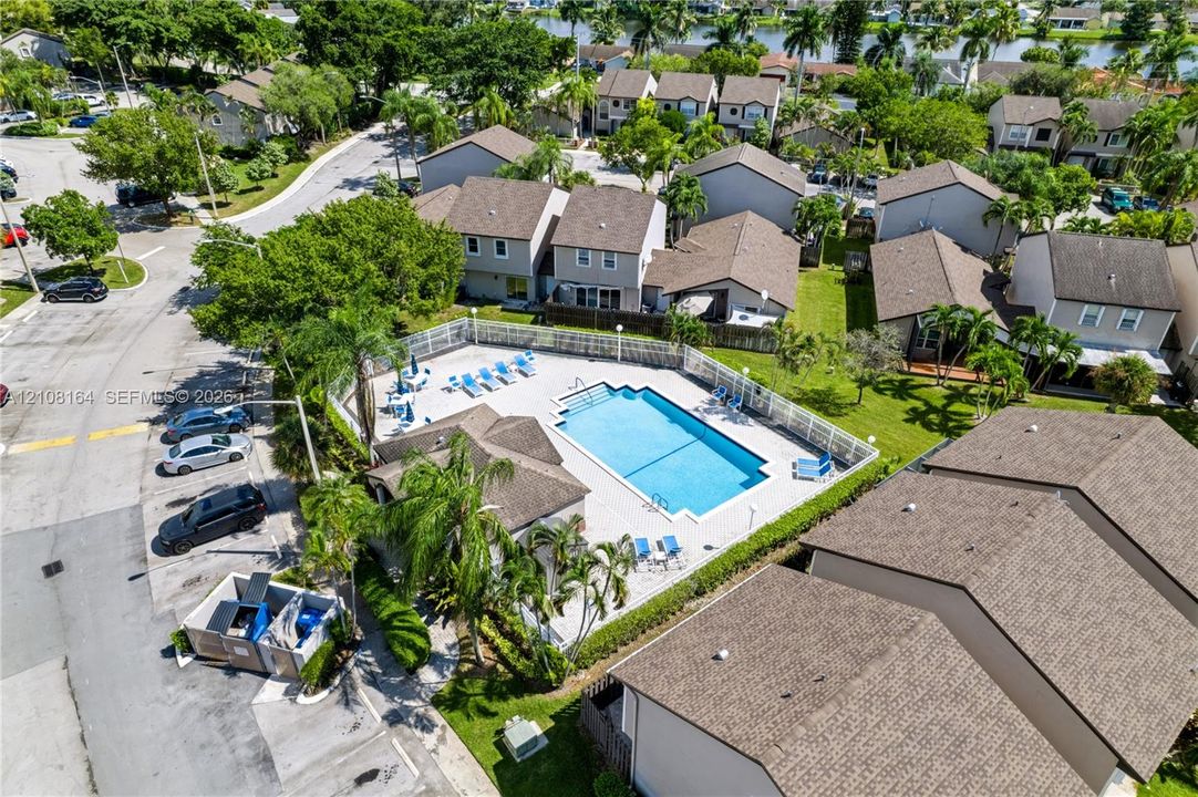 Community swimming pool featuring a concrete deck, perimeter fencing, and surrounding palm trees