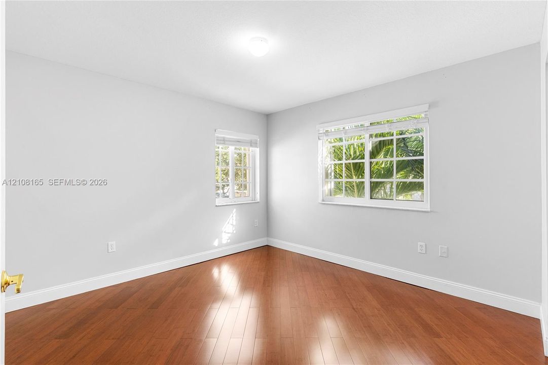 Room featuring wood-finish flooring, dual windows with multi-pane glazing, and neutral wall tones