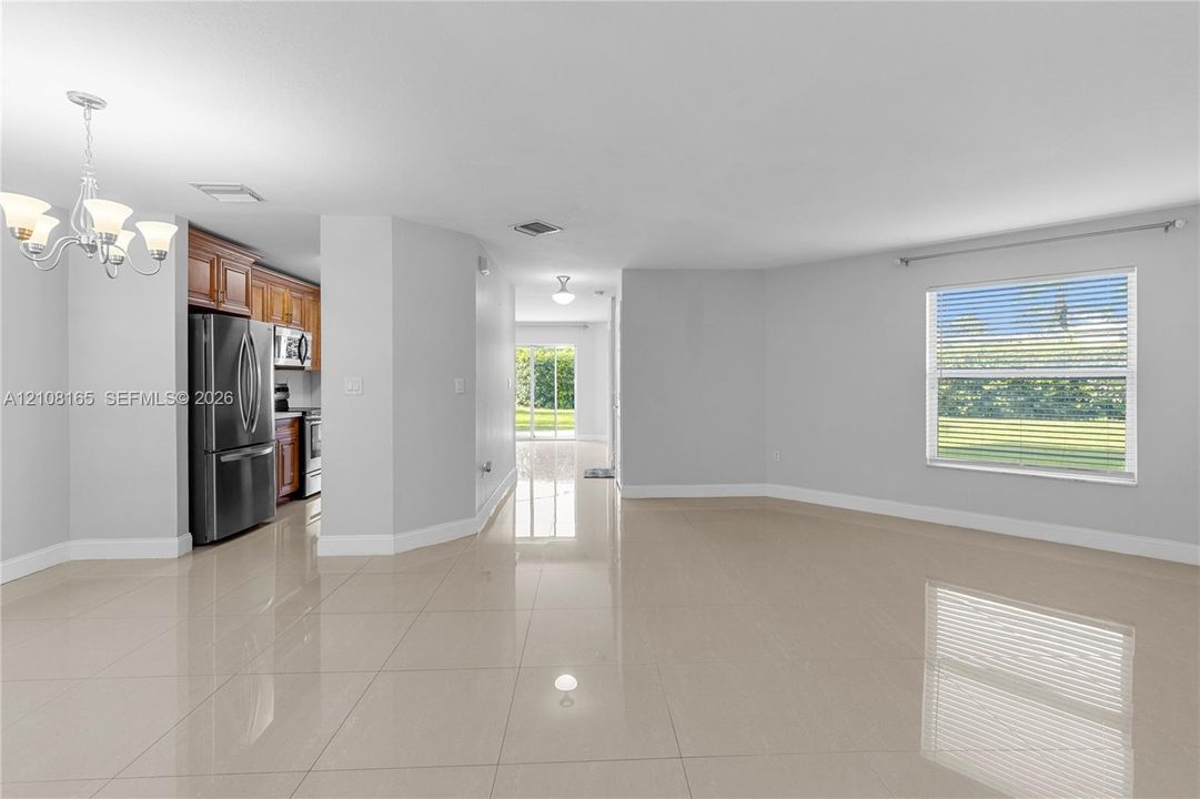 Polished tile flooring, stainless steel kitchen appliances, wood-finish cabinetry, multipane window, and multi-arm chandelier