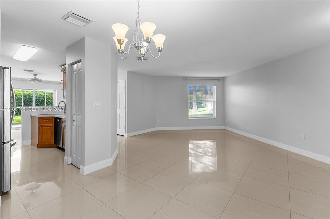 Neutral-toned large-format tile flooring, multi-arm chandelier fixture, natural lighting, and crisp wall finishes