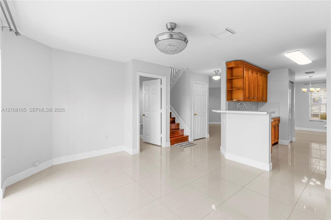 Polished tile flooring, wood-finish cabinetry with a breakfast bar, and decorative ceiling light fixture