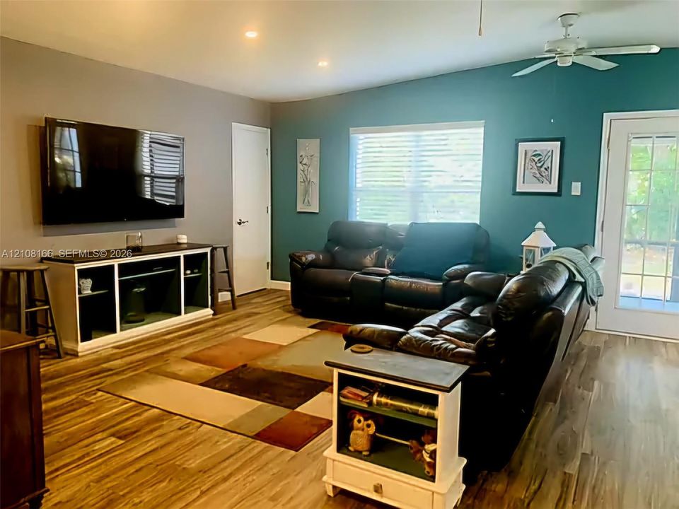 Living area featuring wood-finish flooring, recessed lighting, a ceiling fan, and a glass-paneled exterior door