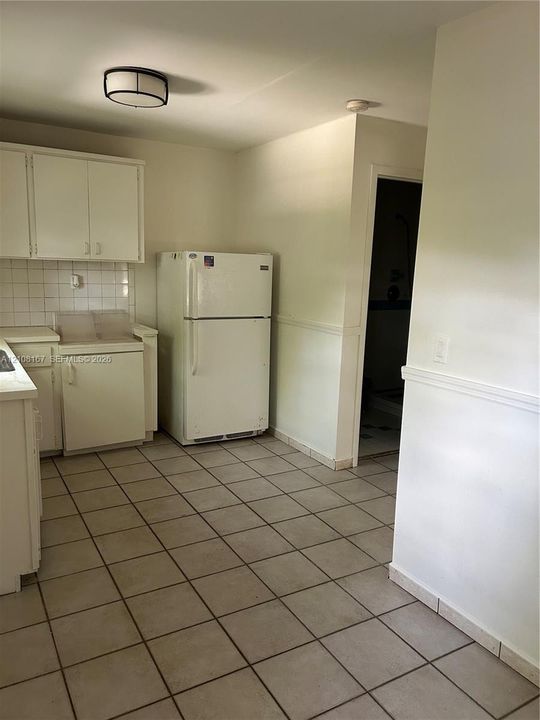 Kitchen featuring white cabinetry, tile flooring, ceramic tile backsplash, and built-in flush-mount ceiling lighting