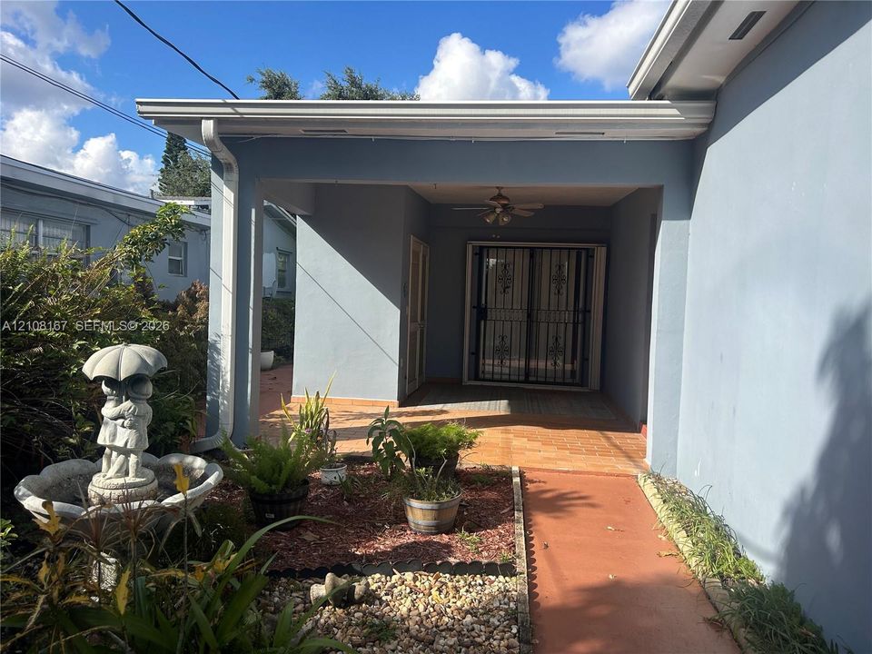 Covered entryway with tile flooring and a ceiling fan, featuring a security screen door and exterior masonry walls