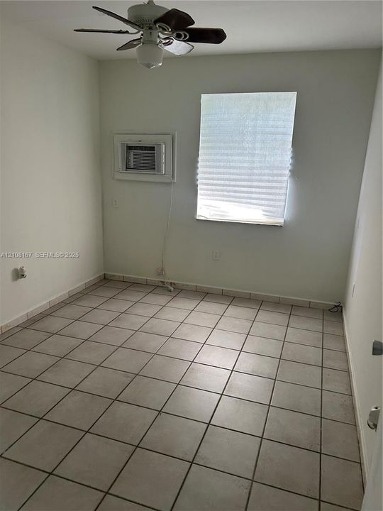 Neutral-toned ceramic tile flooring, ceiling fan with light fixture, and built-in wall-mounted air conditioning unit