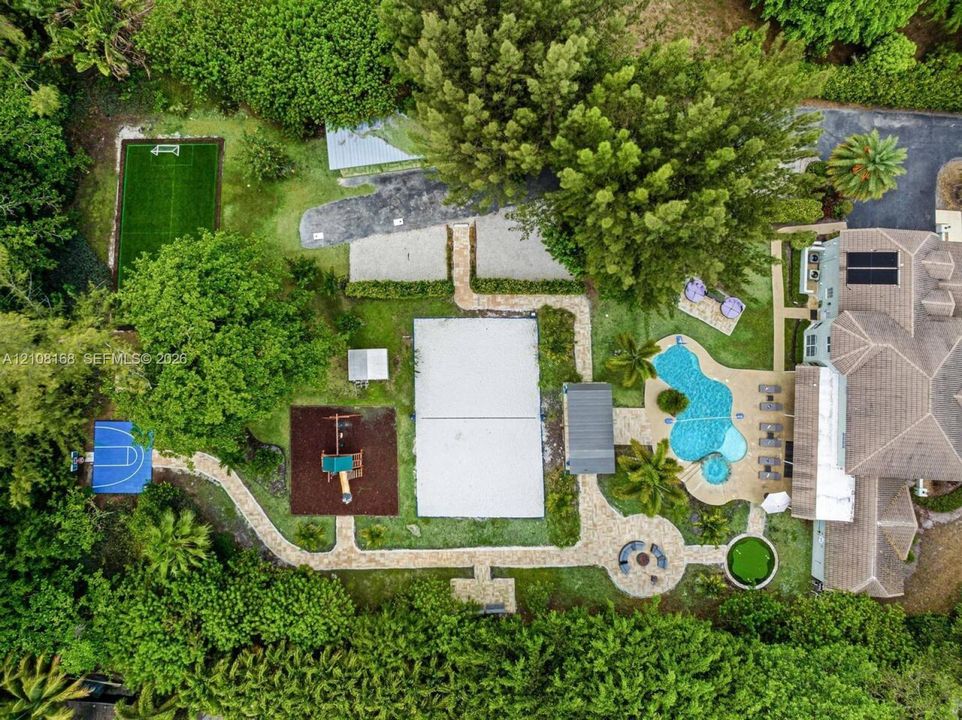 Expansive grounds featuring a swimming pool with integrated spa, multi-sport court, dedicated pickleball court, turf soccer area, and stone-paver walkways