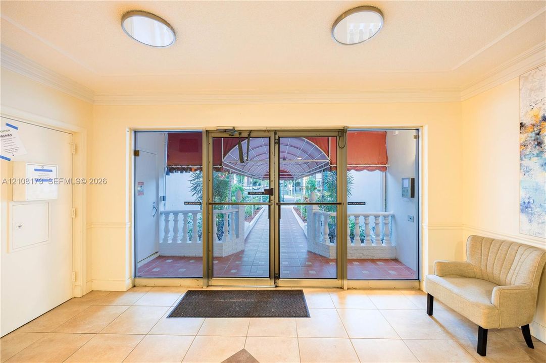 Entrance lobby featuring large-format ceramic tile flooring, recessed circular ceiling lighting, and double-glass entry doors with metal framing