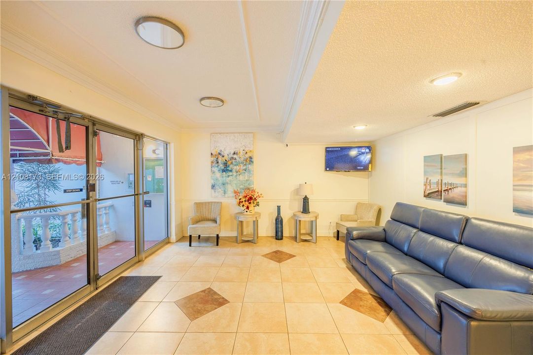 Entrance area featuring glass-panel double doors, ceramic tile flooring with decorative stone accents, recessed ceiling lighting, and chair rail molding
