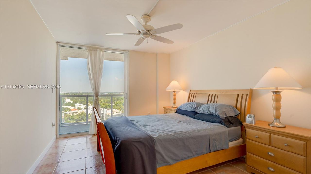 Room featuring tile flooring, a white ceiling fan, and sliding glass doors with a metal railing