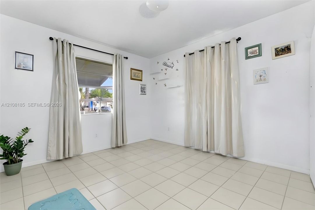 Room featuring neutral tile flooring, dual windows with wall-mounted rods, and overhead flush-mount lighting