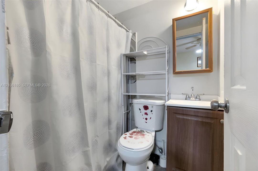Bathroom featuring a wood-finish vanity cabinet, white sink basin, metallic dual-handle faucet, and wall-mounted wooden-framed mirror