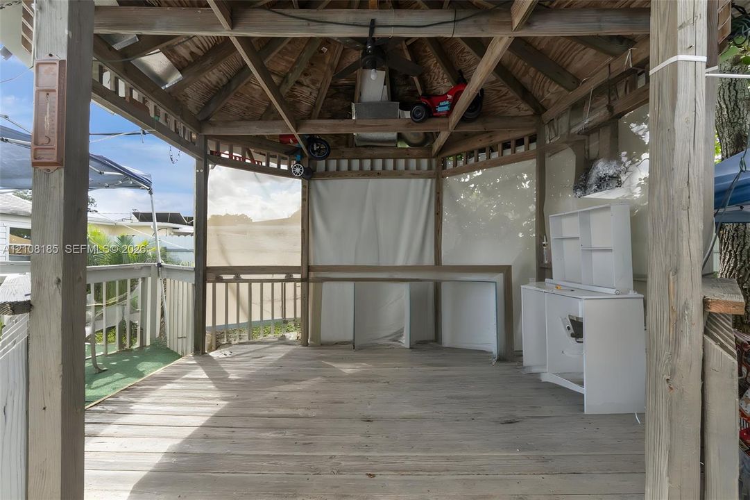 Octagonal gazebo featuring exposed timber framing, a ceiling fan, integrated wooden bar counter, and perimeter railings