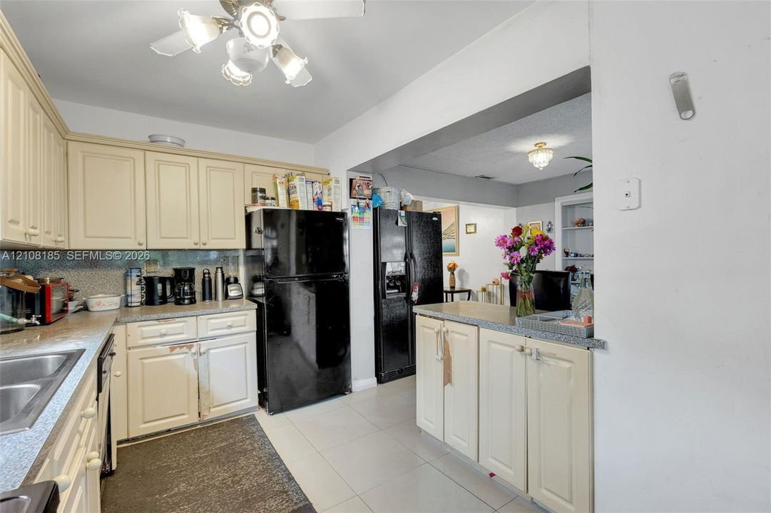 Kitchen featuring off-white cabinetry, stone-finish countertops, tile flooring, and integrated lighting fixtures