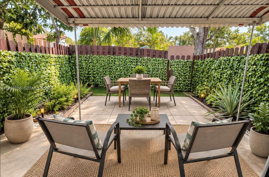 Covered patio featuring large-format concrete pavers, a privacy fence lined with integrated greenery, and low-voltage landscape lighting