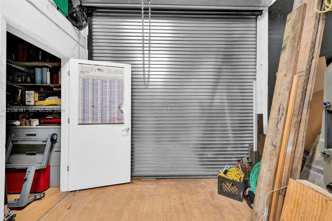 Rolling metal security door, auxiliary entry door, and dedicated storage alcove