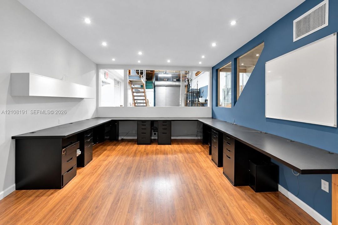 Wood-finish flooring, extensive U-shaped built-in cabinetry, recessed ceiling lighting, and interior glass partitions