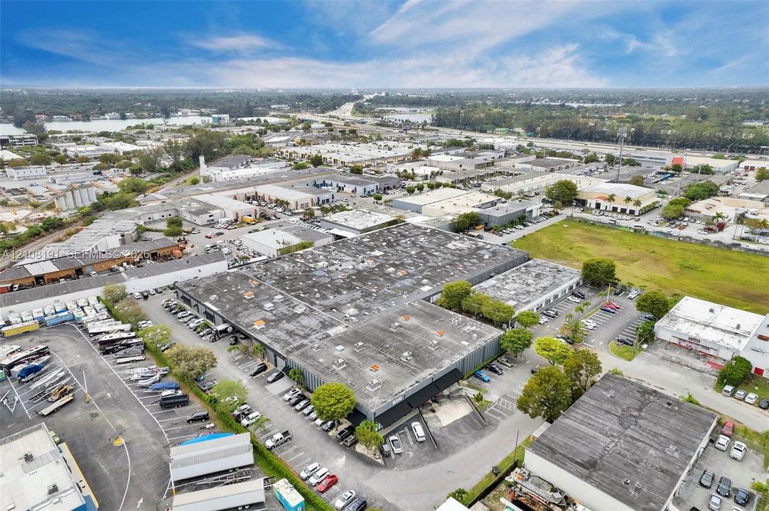 Industrial property featuring a large warehouse facility, expansive parking areas, multiple loading bays, and direct street access