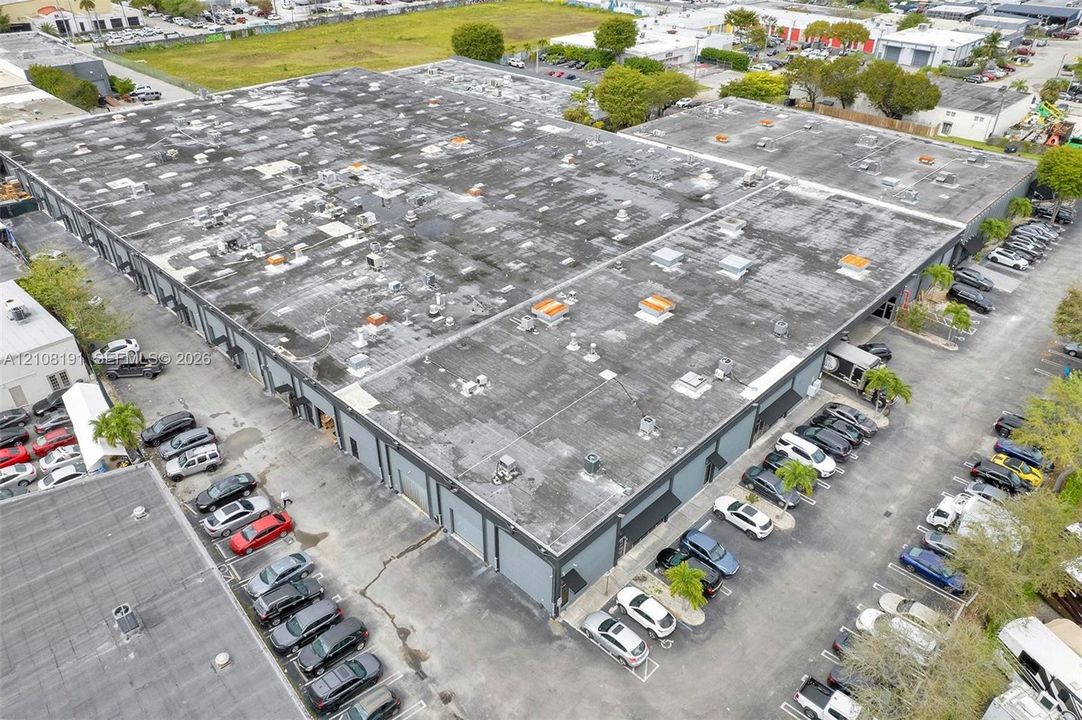 Commercial property featuring a large-format building, multiple ground-level roll-up doors, and an expansive asphalt parking lot with marked stalls