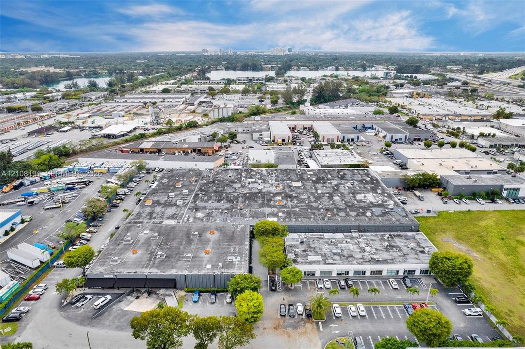 Industrial facility featuring a large-scale flat roof structure, dedicated surface parking, and multiple loading bays situated on an expansive lot with perimeter landscaping